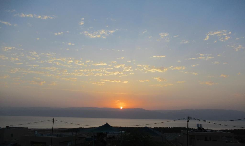 una puesta de sol sobre el océano con el sol en el cielo en Unique&Warmy place in the Dead Sea en Ovnat