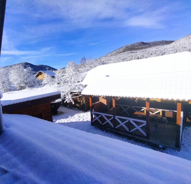 ein schneebedecktes Dach einer Hütte mit schneebedeckten Bergen in der Unterkunft Карпатський Затишок in Huta