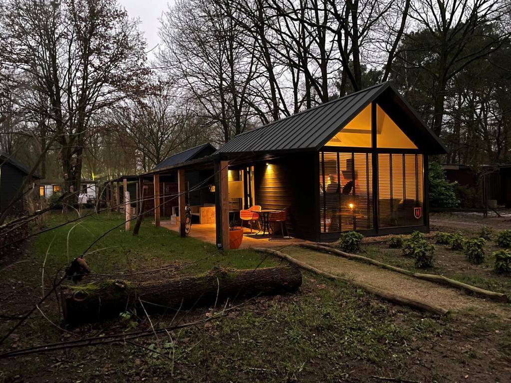 Cosy Tiny Lodges - vakantiepark Kempenbos في Diessen: منزل صغير مع نافذة كبيرة في الفناء