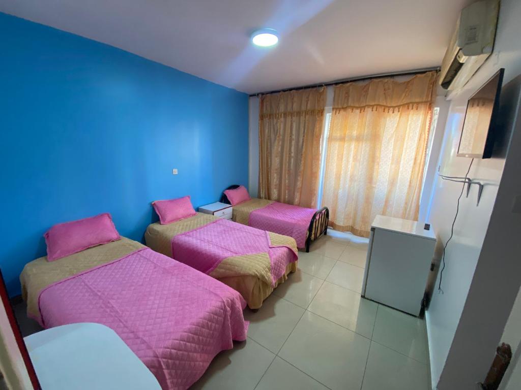 a room with three beds and a blue wall at City Center Hostel in Aqaba