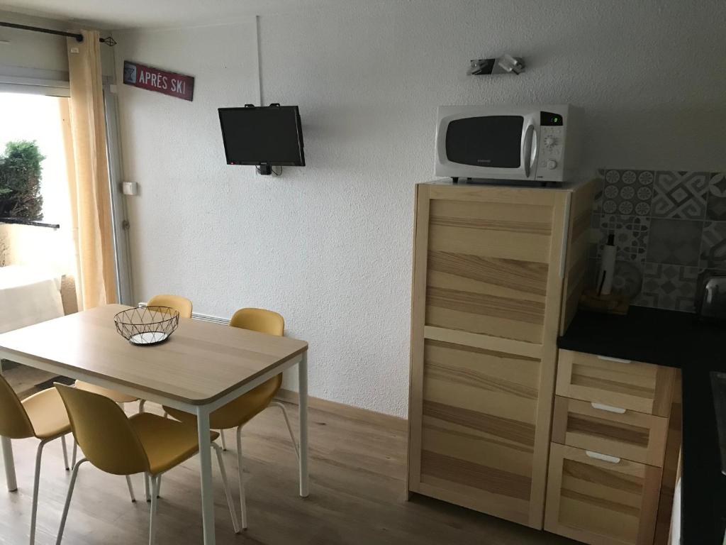 a dining room with a table and a microwave on a cabinet at Appt rénové Saint-Lary-Soulan village avec jardin in Saint-Lary-Soulan