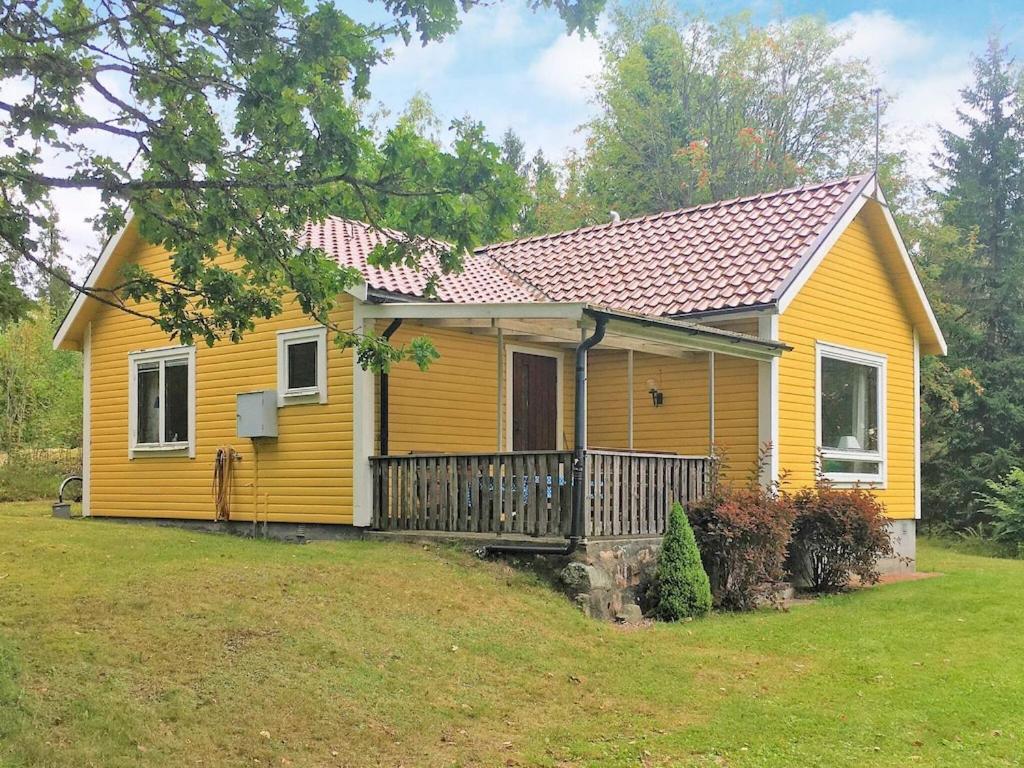 a yellow house with a porch and a yard at 4 person holiday home in R RVIK in Rörvik