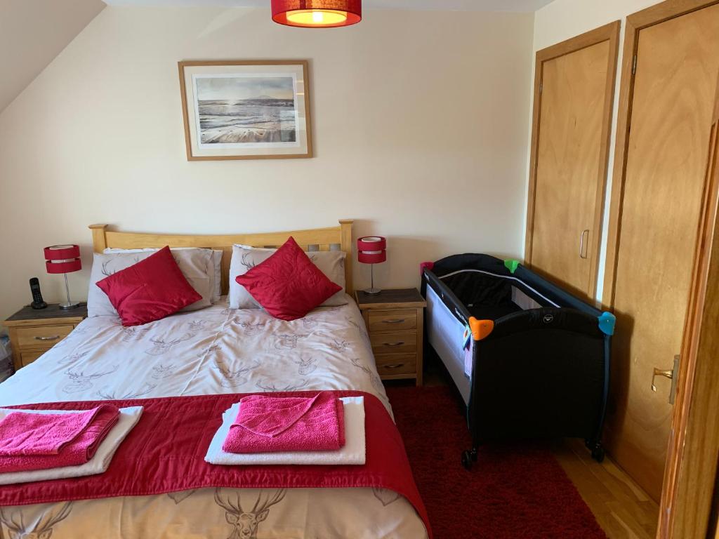 a bedroom with a bed with pink pillows and a suitcase at George's House - 1 Leacklee in Manish