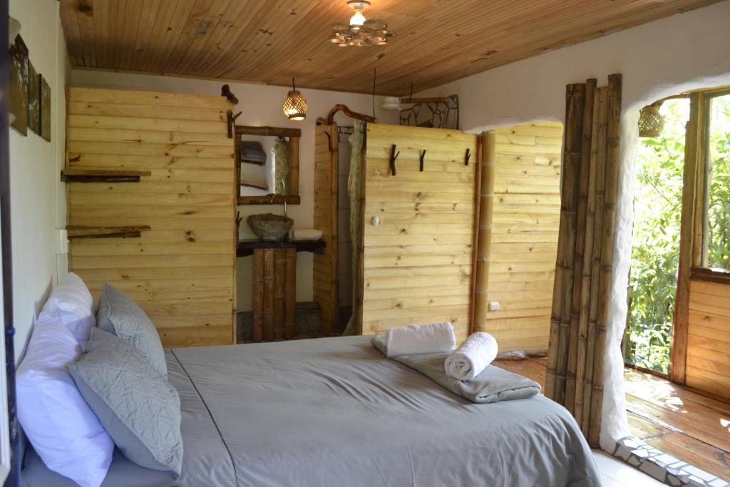 a bed in a room with a wooden wall at Habitación Las Bromelias, Pijao, Finca Flora del Rio in Pijao