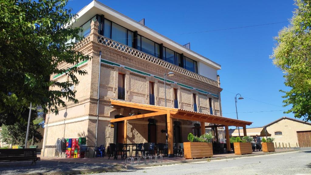 a building with tables and chairs in front of it at Albergue La Estación in Cehegín