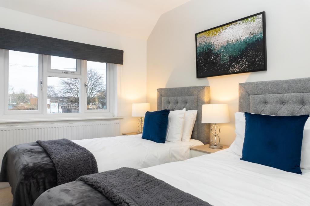 two beds with blue pillows in a bedroom at Relaxation by Olauda SA - 3 Bed House with Free Parking in Bristol