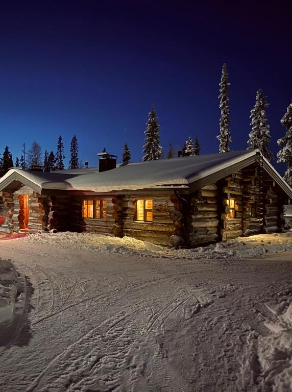 una cabaña de madera en la nieve por la noche en Ruka Chalet Roma, en Ruka