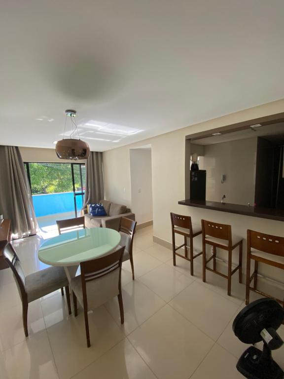 a dining room and living room with a table and chairs at Apartamento 50m da praia no Jd atlântico in Ilhéus