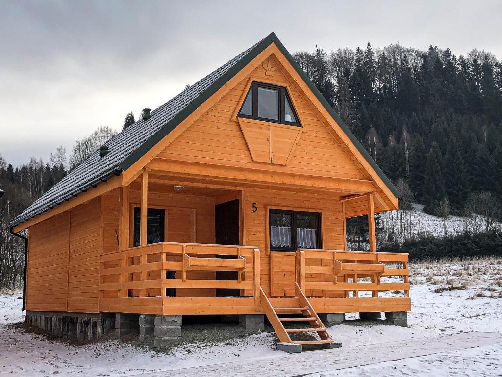 duża drewniana kabina z werandą w śniegu w obiekcie Domki na Podgórzu w mieście Duszniki Zdrój