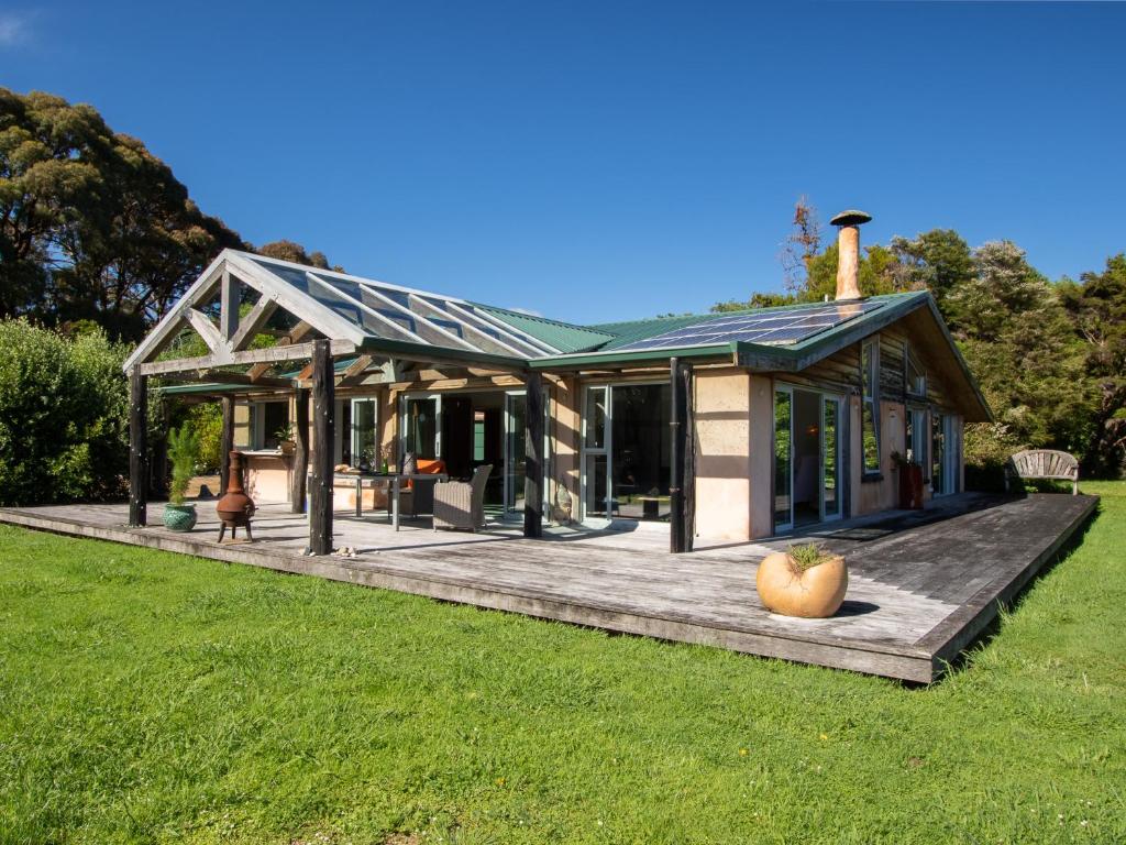 a house with a deck in the grass at Golden Paradise - Rangihaeata Holiday Home in Takaka