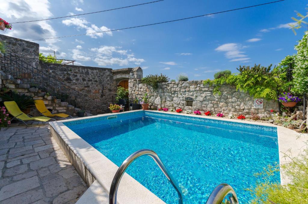 a swimming pool in a yard with a stone wall at House Villa Ljuba in Crikvenica