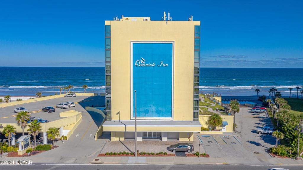 a building with a sign on it next to the ocean at Oceanside Inn Hotel in Daytona Beach Shores