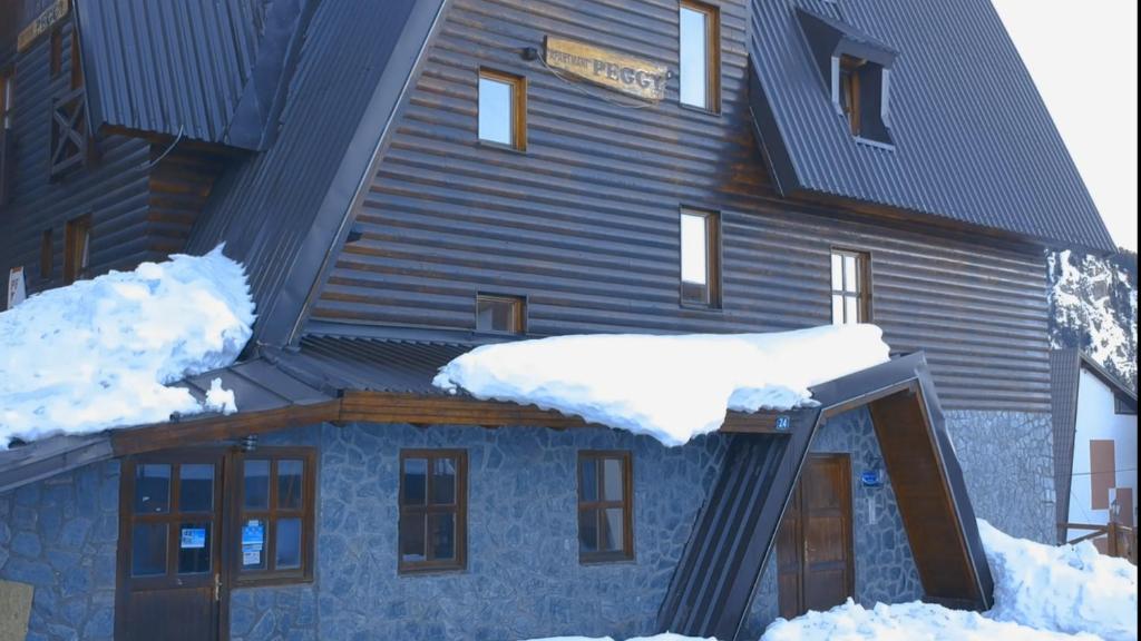 a house covered in snow with snow on the roof at Apartments Peggy in Jahorina