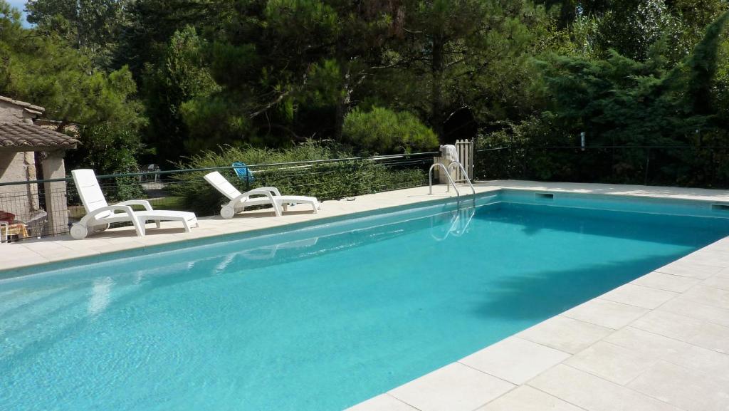 una piscina con 2 tumbonas y una piscina en Mas Grimaud - Gîte- Studio et chambres d'hôtes familiales, en Eygalières