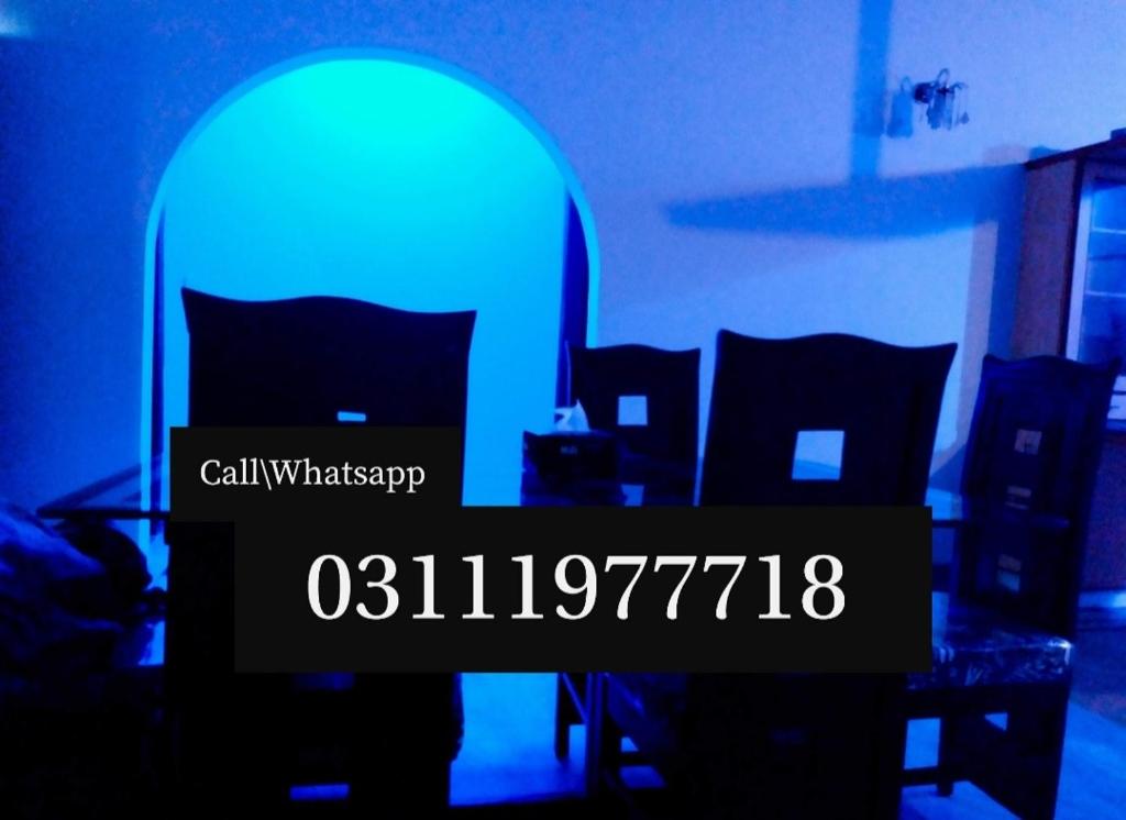 Cette chambre comprend une table et des chaises avec une lumière bleue. dans l'établissement Gulshan Guest House Karachi, à Karachi