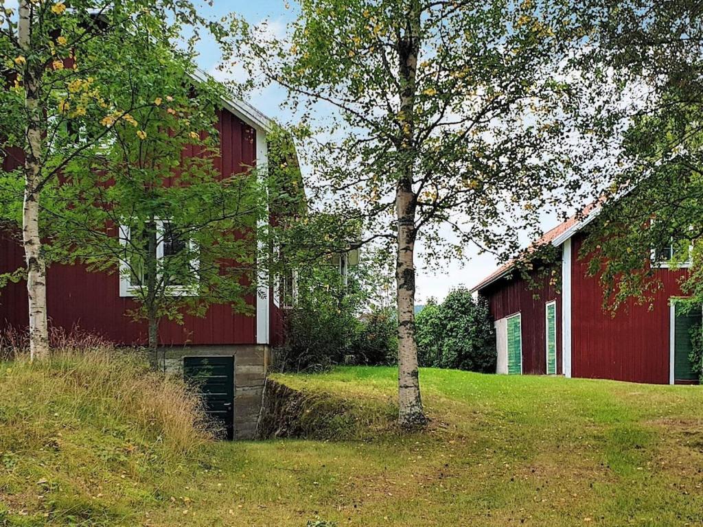 a red barn with a tree in front of it at 4 person holiday home in J RVS in Järvsö