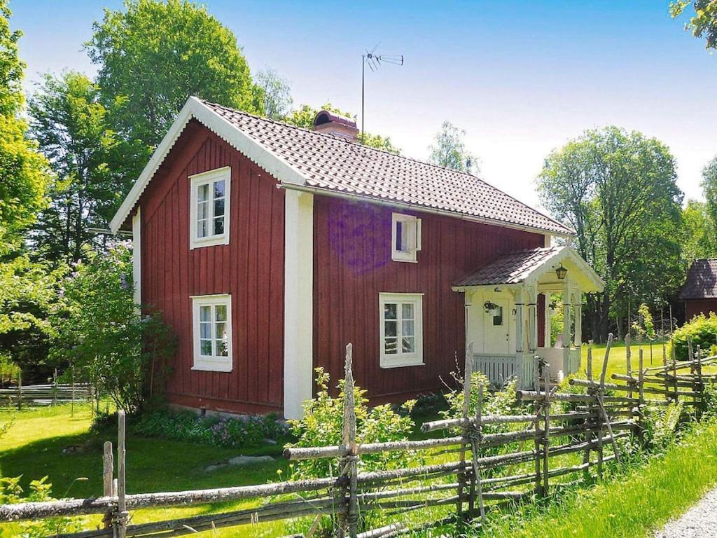 een rood-wit huis met een houten hek bij 5 person holiday home in LAMMHULT in Lammhult