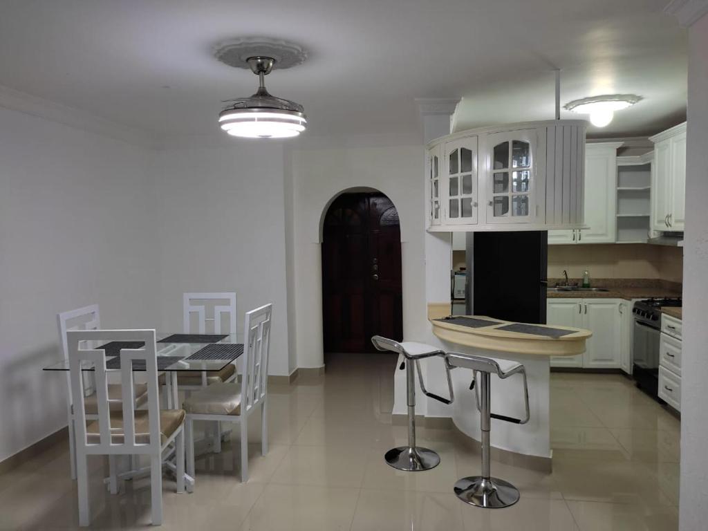 a kitchen with white cabinets and a table and chairs at Galerias Pelush 2 beedroom in San Pedro de Macorís