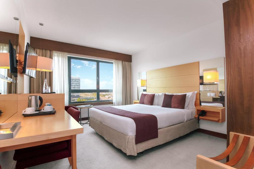 a hotel room with a large bed and a desk at Hotel Acores Lisboa in Lisbon