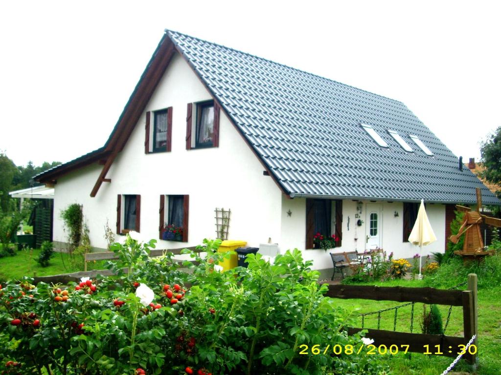 ein weißes Haus mit schwarzem Dach und ein paar Blumen in der Unterkunft Haus Rehwiese in Benz