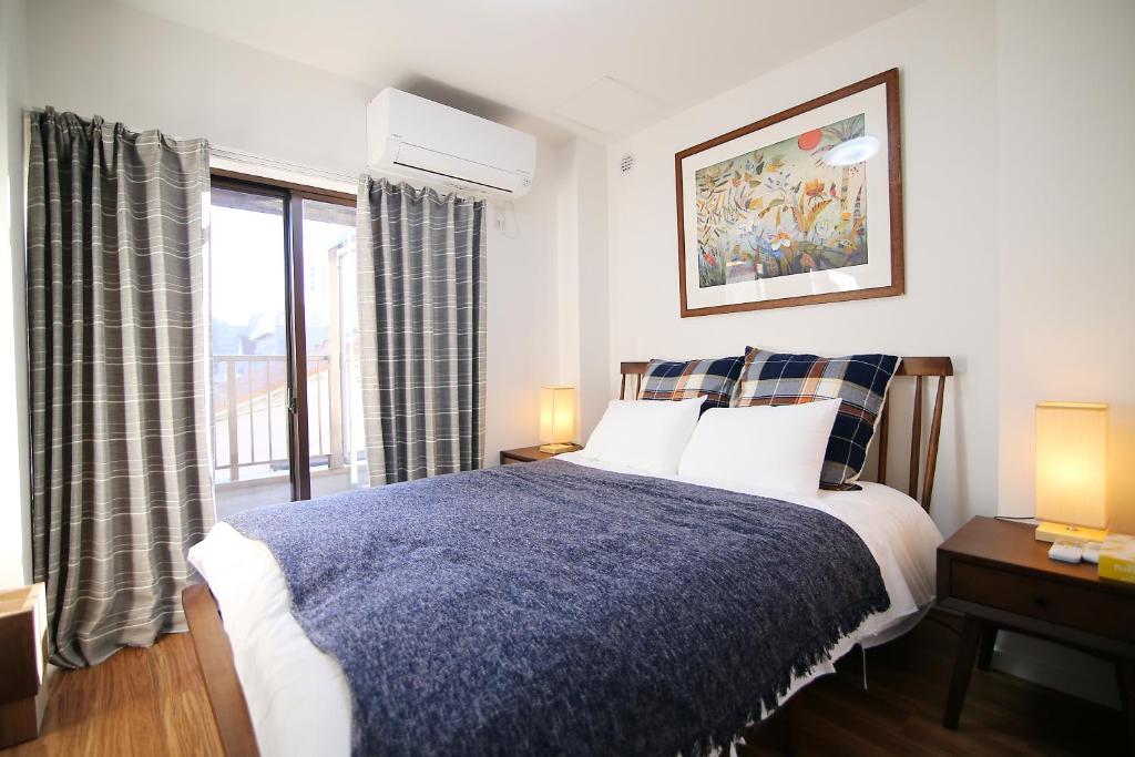 a bedroom with a bed and a large window at MUMU HOUSE in Tokyo