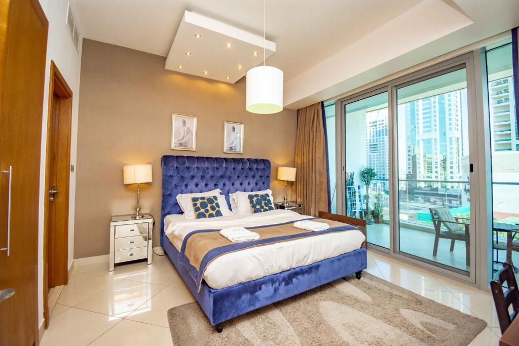 a bedroom with a blue bed and a large window at Stylish and Sleek 1 Bed + Study near the JBR beach in Dubai