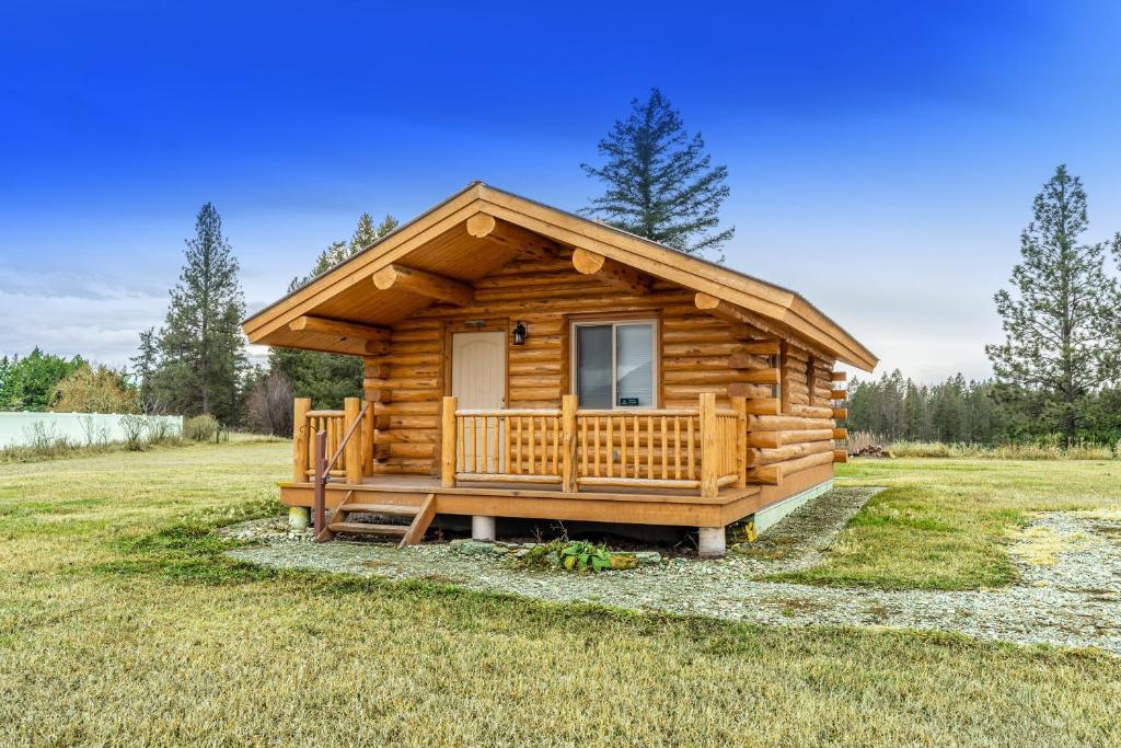 Cabaña de madera con porche en un campo en Hidden Haven Cabin en Columbia Falls