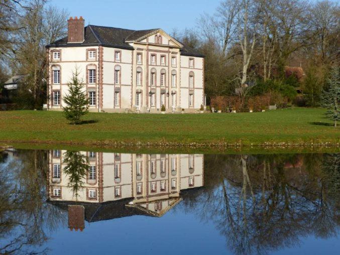 una casa grande con su reflejo en el agua en Chambre Le Notre Le Domaine Des Jardins De Bracquetuit, en Bracquetuit