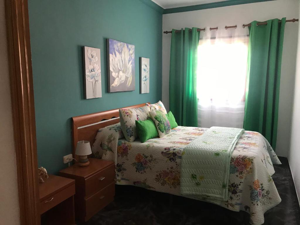 Un dormitorio con una cama con paredes verdes y una ventana en La Casita de Omar en el corazón de Anaga y La Laguna en Las Mercedes