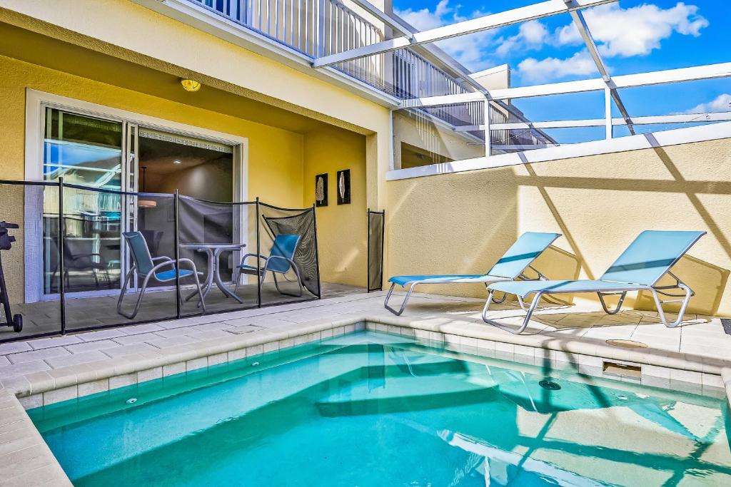 a swimming pool with two chairs and a table at Retreat Magic in Orlando