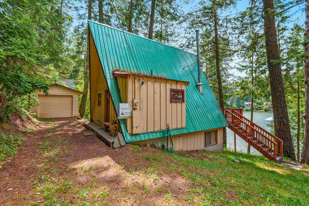 ein Haus mit einem grünen Dach im Wald in der Unterkunft Kidd Island Bay Cabin Retreat in Coeur d'Alene