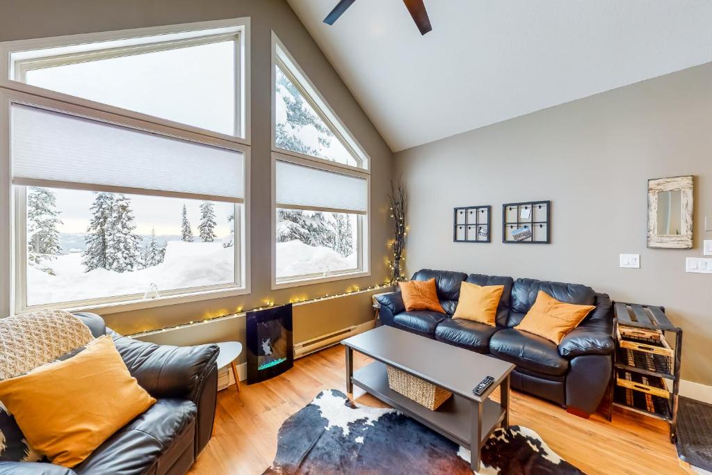 una sala de estar con un sofá y una mesa en Snow Pines & Ice and Cozy, en Big White