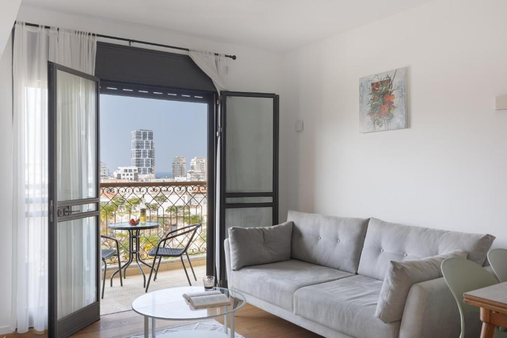 un soggiorno con divano e balcone di Elegant Apartment w Balcony & Mamad in Heart of Tel Aviv by Sea N' Rent a Tel Aviv