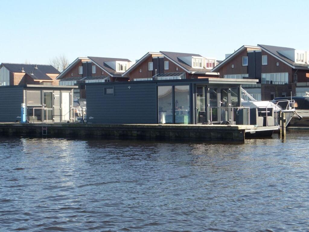 a house on a dock next to the water at Modern houseboat with air conditioning located in marina in Uitgeest