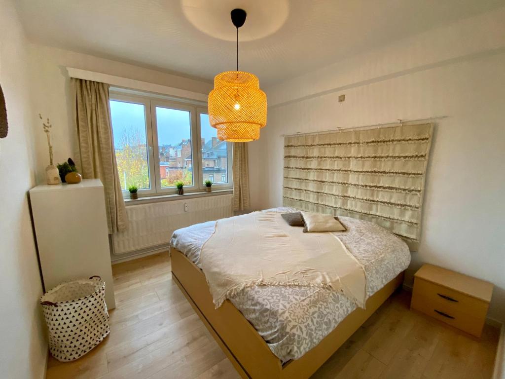 ein Schlafzimmer mit einem Bett und einem großen Fenster in der Unterkunft Appartement lumineux, idealement situe - Enfants bienvenus ACTIVITES COMMERCIALES OU REMUNEREES INTERDITES in Namur