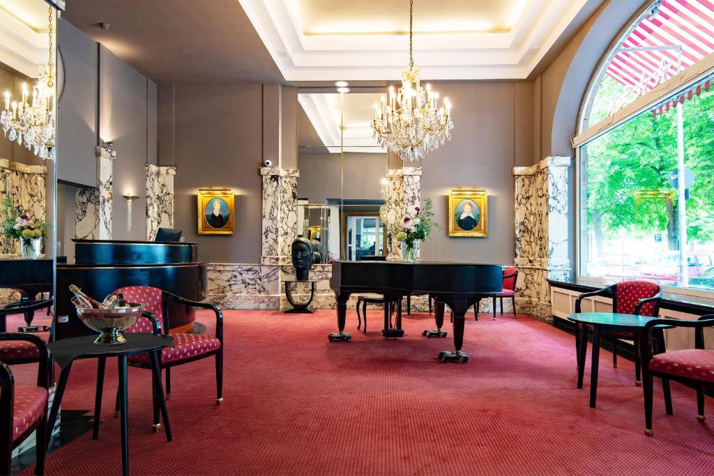 a living room with a grand piano and chairs at Hotel Bamberger Hof Bellevue in Bamberg