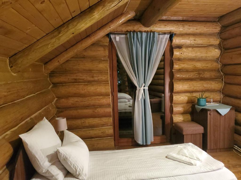 a bedroom in a log cabin with a bed and a window at Papa la Șoni Gastro-Pensiune in Borsec