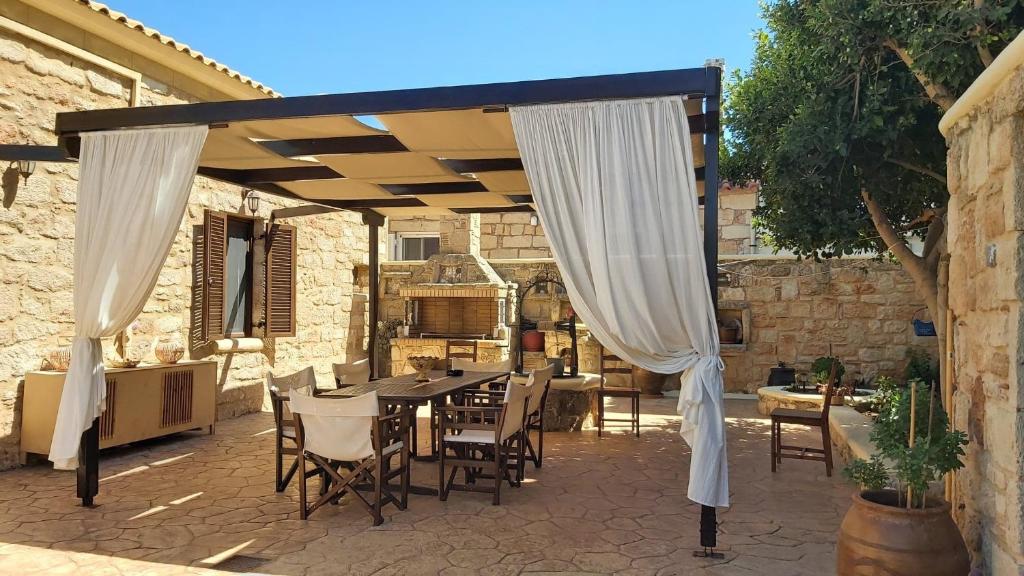 eine Terrasse mit einem Tisch und Stühlen unter einem Baldachin in der Unterkunft Christakos stone house Elafonisos in Elafonisos