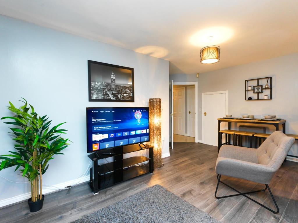 uma sala de estar com uma televisão de ecrã plano e uma cadeira em Rothwell Close Serviced Two Bed Apartment em Telford