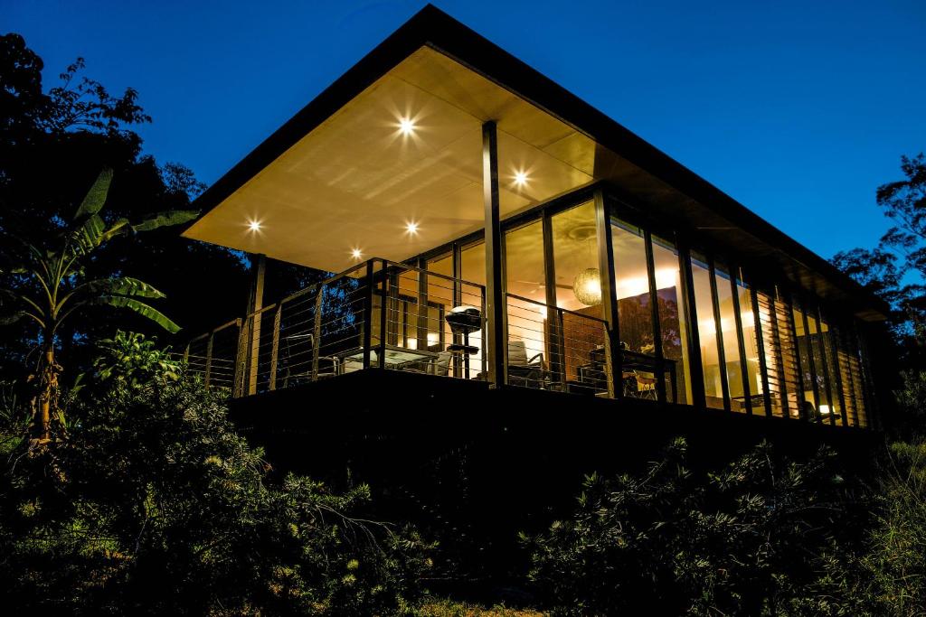 a house with large glass windows at night at Glass On Glasshouse in Glass House Mountains