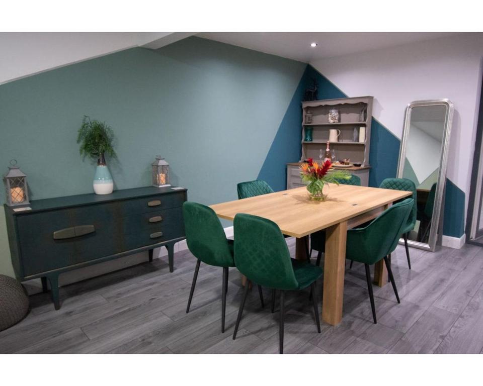 comedor con mesa de madera y sillas verdes en Ideal Lodgings in Baxenden, en Accrington