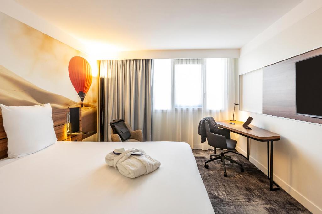 
a hotel room with a bed, chair, desk and a television at Novotel Bordeaux Centre Gare Saint Jean in Bordeaux
