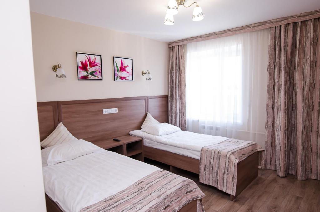 um quarto de hotel com duas camas e uma janela em Uralochka Hotel em Chelyabinsk