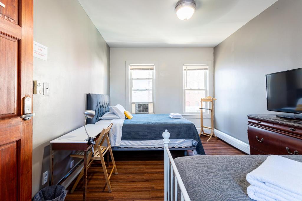 a room with two beds and a flat screen tv at Best Home To Visit NYC-Subway Access in Newark