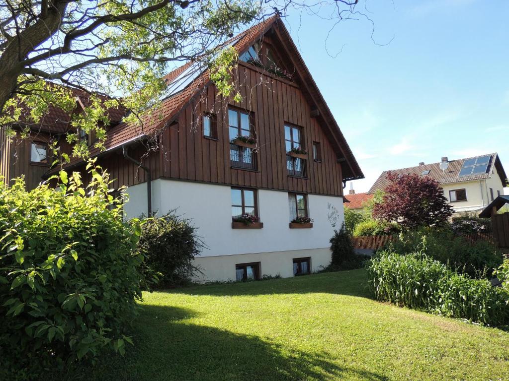 een huis met een houten dak en een groene tuin bij Gästehaus Jutta / Pension Link in Fladungen
