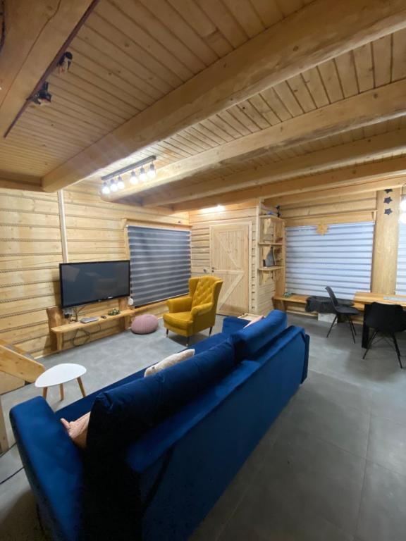 a living room with a blue couch and a tv at Nagano - klimatyczny domek w górach in Korbielów