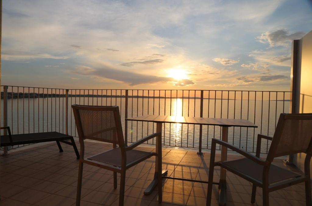 einen Tisch und Stühle auf einem Balkon mit Blick auf den Sonnenuntergang in der Unterkunft mk apartments nin Wohnung 8 in Kod Mula