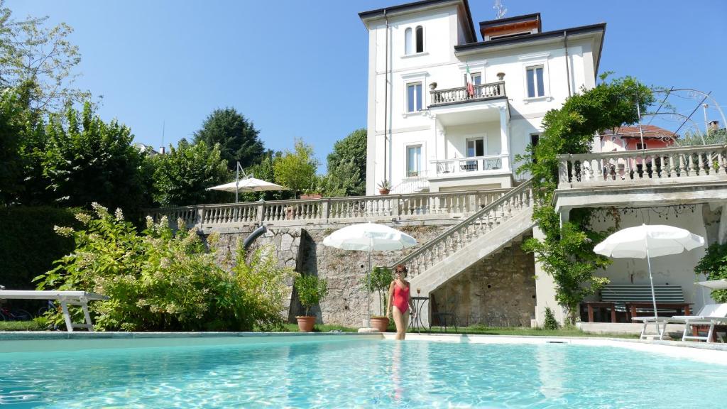 une personne debout dans une piscine en face d'un bâtiment dans l'établissement White Lilac Romantic B&B - Adults only, à Arona