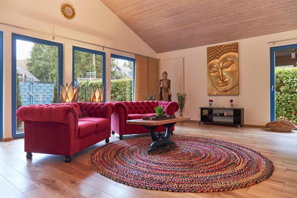 sala de estar con sofá rojo y mesa en Bio-Ferienhaus-Eifel, en Rott
