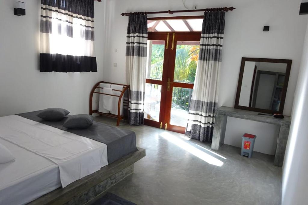 a bedroom with a bed and a mirror and a window at Sudu Guest in Habaraduwa Central